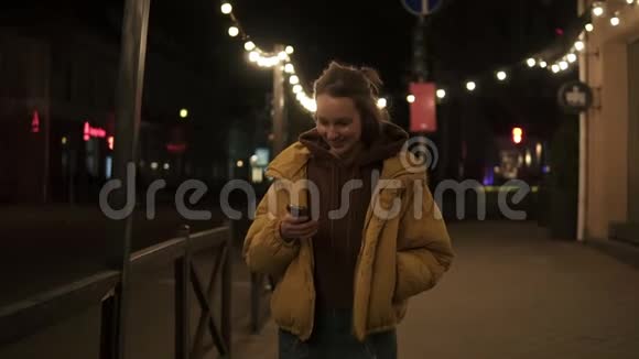 短发女孩微笑着穿过晚城停下来在智能手机上发短信手持录像视频的预览图