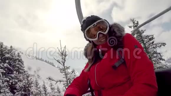 女子滑雪者爬上椅子抬到山顶显示拇指向上视频的预览图