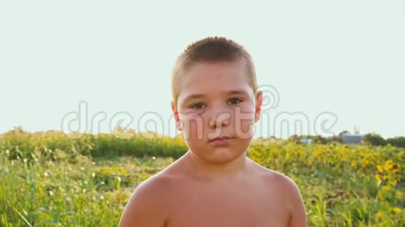 一个胖乎乎的男孩的肖像黑眼睛的背景是一片绿色的田野一个悲伤的孩子赤裸的躯干和一个视频的预览图