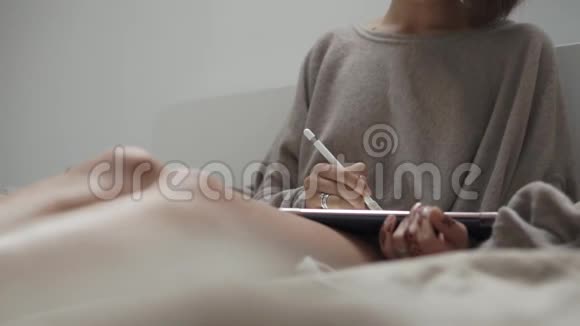 一个女人坐在沙发上用便携式平板电脑工作的近距离镜头视频的预览图