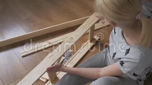 女家庭主妇坐在地板上的房间里收集木架在商店里买的家具组装视频的预览图