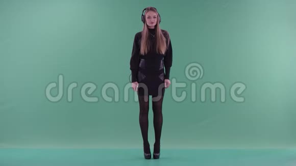 穿着黑色便服的年轻美女在绿色屏幕前听音乐跳舞视频的预览图