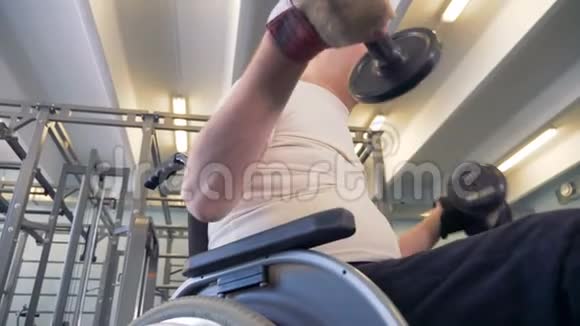 残疾人在锻炼时看着他握着哑铃的手视频的预览图