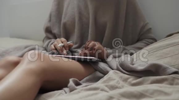 优雅的女孩正坐在床上在触摸屏电脑键盘上输入文字视频的预览图