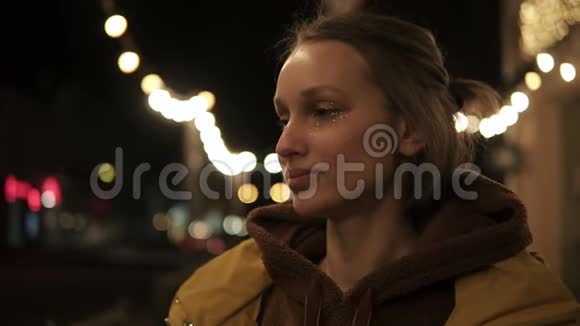 街上漂亮的年轻女子穿着黄色外套转身对着镜头闪闪发光后面的灯光视频的预览图