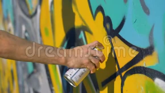 艺术家右手正在墙上画一个黄色的字母从右边近距离观看视频的预览图