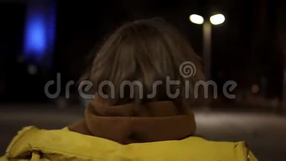 一个年轻的女孩勇敢地旋转把一件黄色的夹克扔在她的头上玩得很开心跳跃视频的预览图