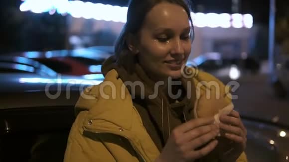 快乐的微笑女孩脸上闪着火花在夜街吃汉堡包手持录像视频的预览图