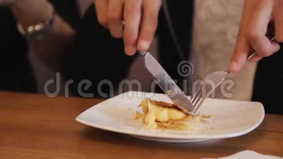 男性用叉子和刀在白色盘子上切蛋糕年轻人在咖啡馆里吃美味的蛋糕视频的预览图