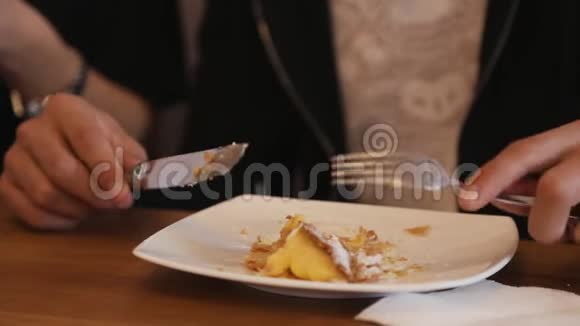 男性用叉子和刀在白色盘子上切蛋糕年轻人在咖啡馆里吃美味的蛋糕视频的预览图