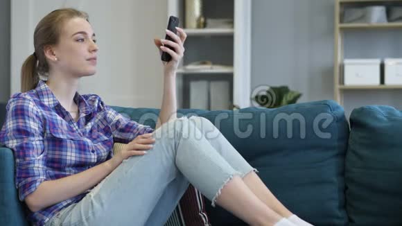 年轻女子在沙发上放松时打电话视频的预览图