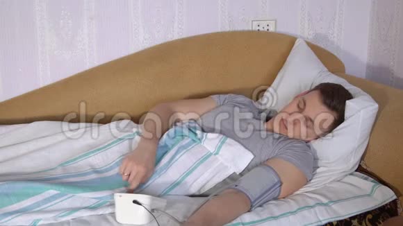 躺在床上的年轻人用电子测压仪测量压力视频的预览图