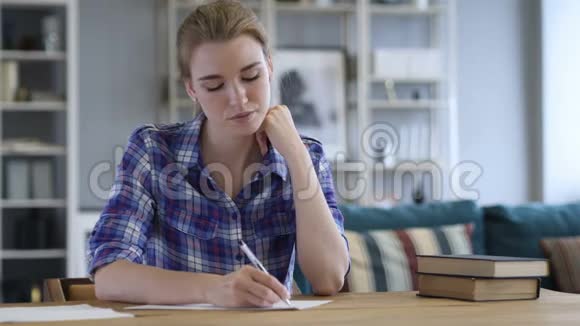 疲惫的年轻女子在写文件时放松视频的预览图
