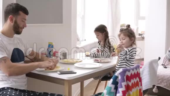 年轻的家庭在家厨房和两个女儿一起吃早餐聊天视频的预览图