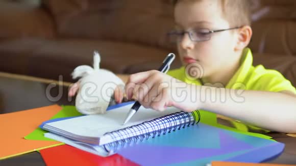 戴眼镜断手的男孩试图用左手做作业视频的预览图