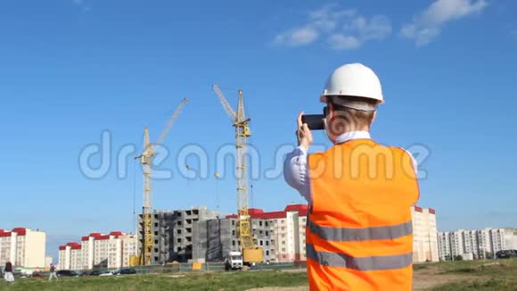 一位戴着白色头盔和一件警服的检查员正在拍摄一栋公寓大楼的建造情况视频的预览图