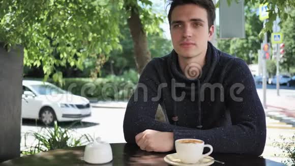 坐在咖啡馆露台上哭泣悲伤的年轻人的肖像视频的预览图