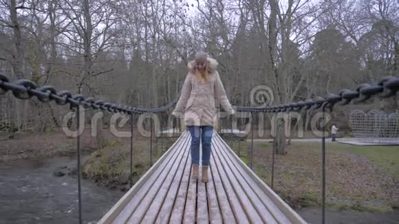 在吊桥上行走的美女开始在桥上跳跃尽情享受视频的预览图