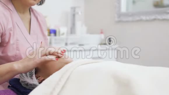美容师在面部按摩前病人的嘴唇涂上保护膏视频的预览图