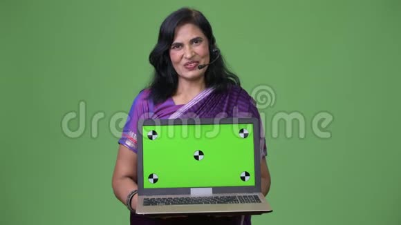 成熟快乐美丽的印度女人呼叫中心代表一边说话一边展示笔记本电脑视频的预览图