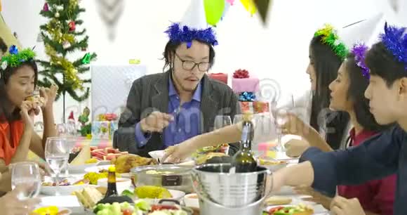 一群亚洲人在新年聚会上一起在餐桌上品尝美味的食物庆祝圣诞节视频的预览图