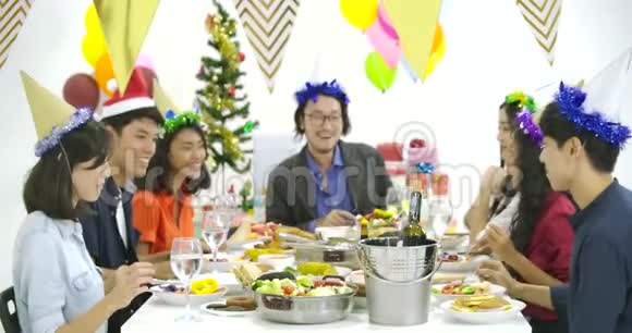 一群亚洲人在新年聚会上一起在餐桌上品尝美味的食物庆祝圣诞节视频的预览图
