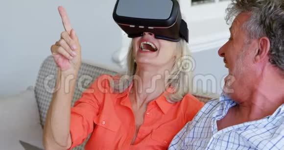 高级夫妇在4k沙发上使用笔记本电脑和虚拟现实耳机视频的预览图