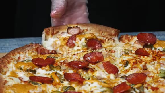 厨师的贴身保护手套拿一块美味的披萨和沙拉米泡菜奶酪在木制的视频的预览图