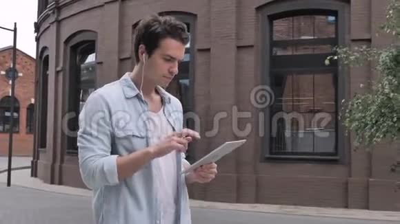 男子在街上散步在桌上跳舞和听音乐视频的预览图