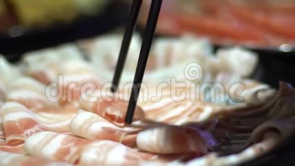 牛肉生肉拿筷子火锅与甜甜圈形状的黄铜锅视频的预览图