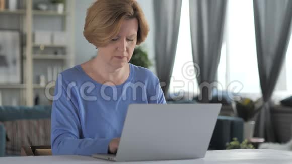 兴奋的老年妇女庆祝成功在笔记本电脑上工作视频的预览图