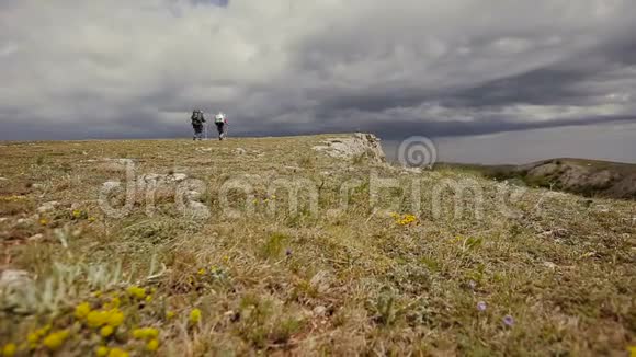 徒步情侣人们徒步山年轻的男人在春天沿着悬崖边散步徒步旅行者夫妇视频的预览图
