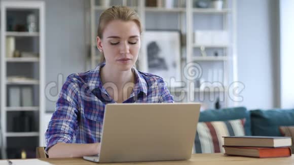 青年妇女在笔记本电脑上工作在办公室里坐沙发视频的预览图