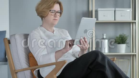 坐在沙发上的老年妇女在餐桌上的在线视频聊天视频的预览图
