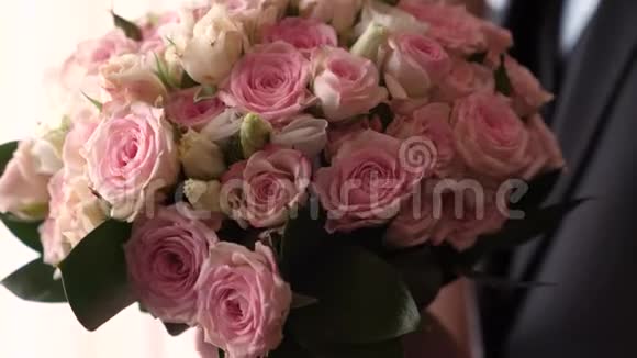 男人手里捧着一束美丽的五彩玫瑰穿西装的人要和漂亮的花约会特写视频的预览图