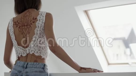 少年背部的后视图她用指甲花的纹身装饰她的身体视频的预览图