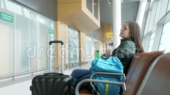 年轻疲倦的妇女正坐在大厅里等飞机视频的预览图
