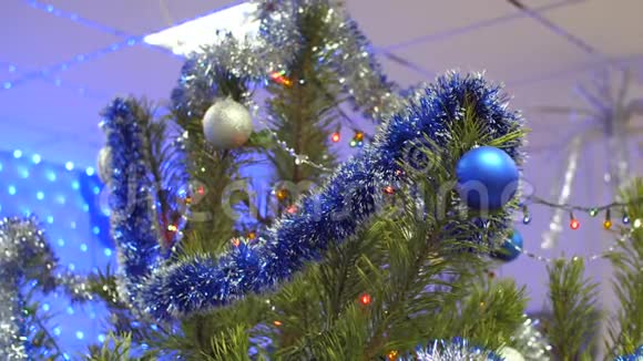 房间里有一棵漂亮的圣诞树上面装饰着花环多种颜色的球和金属视频的预览图