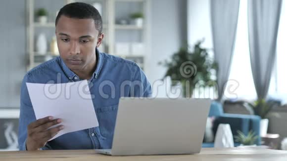 青年非洲男子在办公室工作文件和笔记本电脑视频的预览图