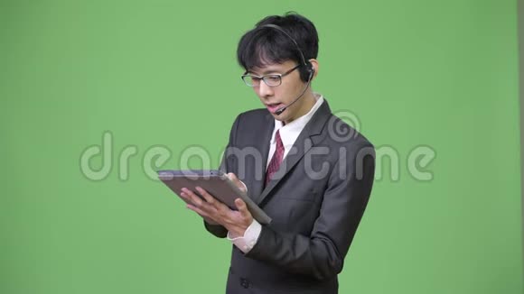 年轻快乐的亚洲商人在呼叫中心工作时使用数字平板电脑视频的预览图