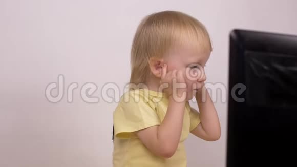 白种人小女孩金发碧眼地看着电脑笔记本电脑的笑声和鬼脸特写情绪视频的预览图