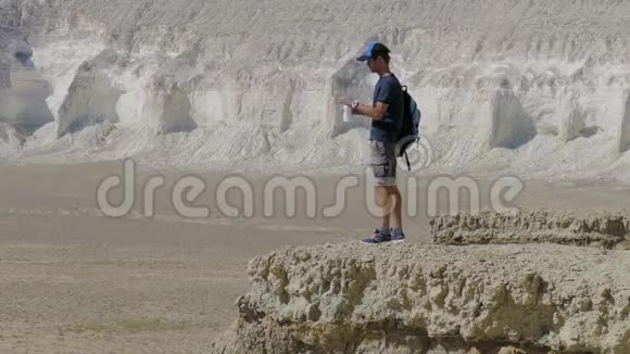 一个年轻的旅行者在岩石上喝水视频的预览图
