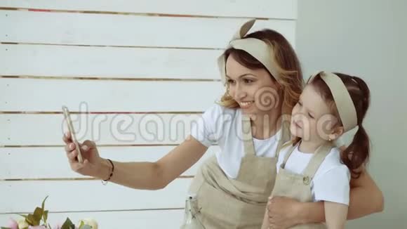 一个小女孩和她妈妈在智能手机上自拍视频的预览图