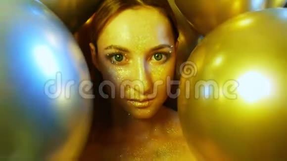 特写女孩脸上金色的亮片放在金色气球里视频的预览图