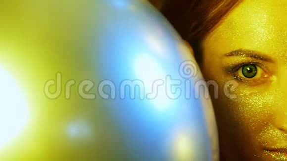 特写女孩脸上金色的亮片放在金色气球里视频的预览图