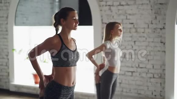 年轻的女性瑜伽教练正在展示平衡姿势和与学生交谈的顺序而其他女性则在视频的预览图