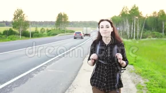 Hitchhiker女孩带着旅游背包在路上行走视频的预览图