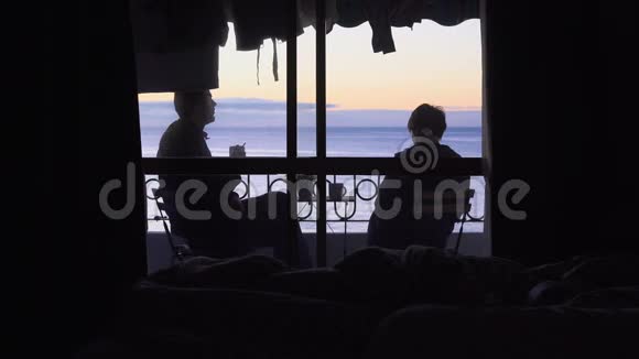 一个年轻的女人和男人从酒店阳台上看大海日出喝茶视频的预览图
