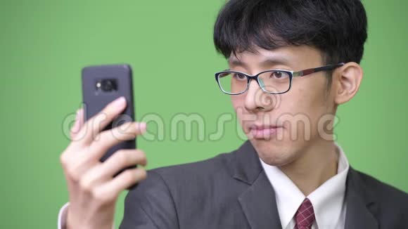 年轻的亚洲商人用手机触摸屏幕视频的预览图
