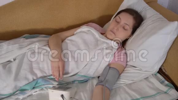 床上的年轻女子用电子测压仪测量压力视频的预览图